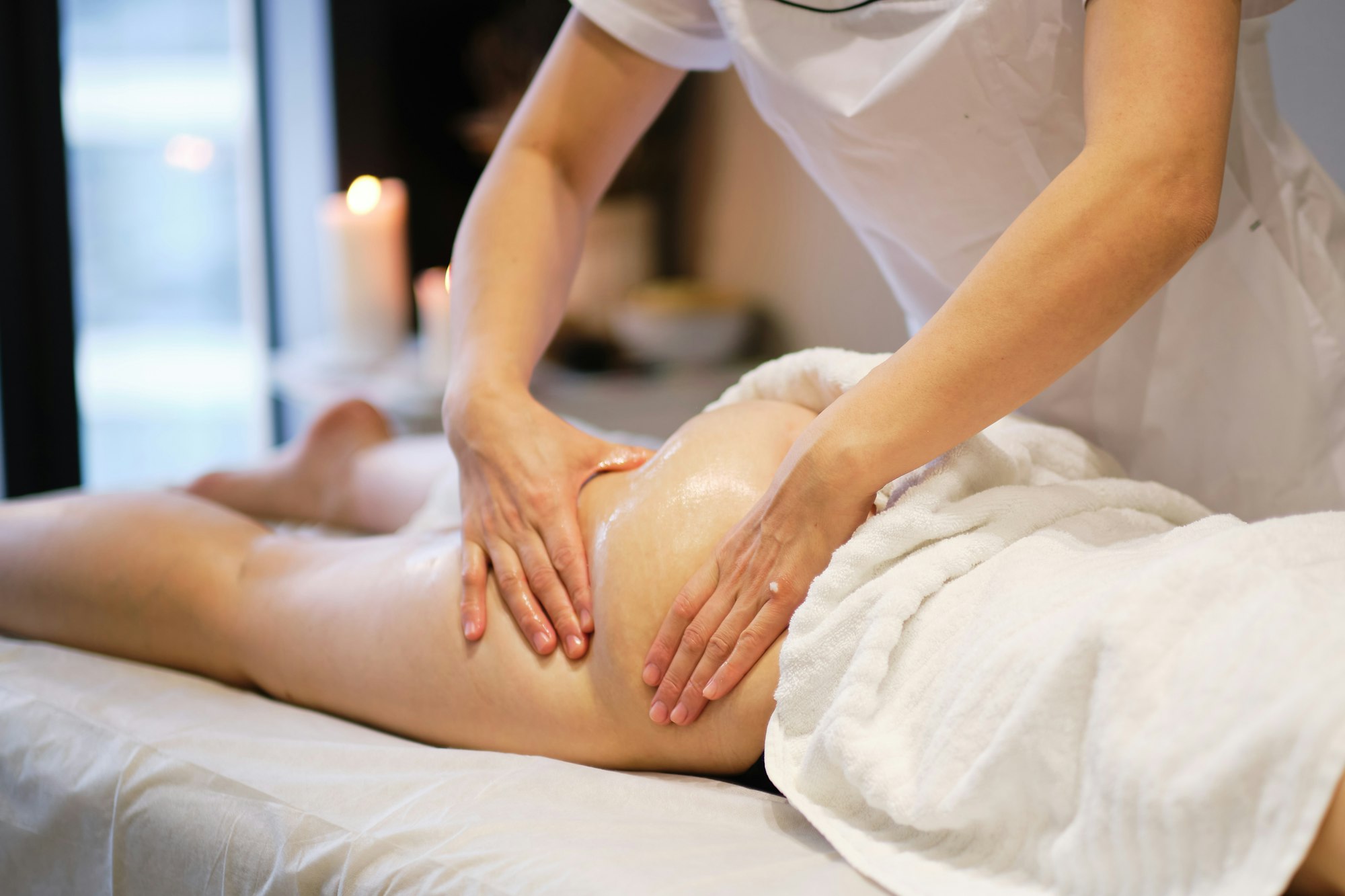Relaxed woman receiving anti-cellulite massage from a therapist on massage table